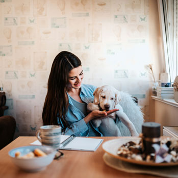 woman holding a puppy eating a treat