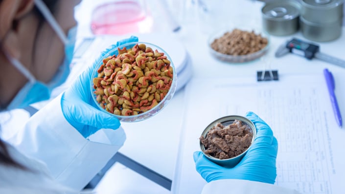 scientists holding two bowls of pet food