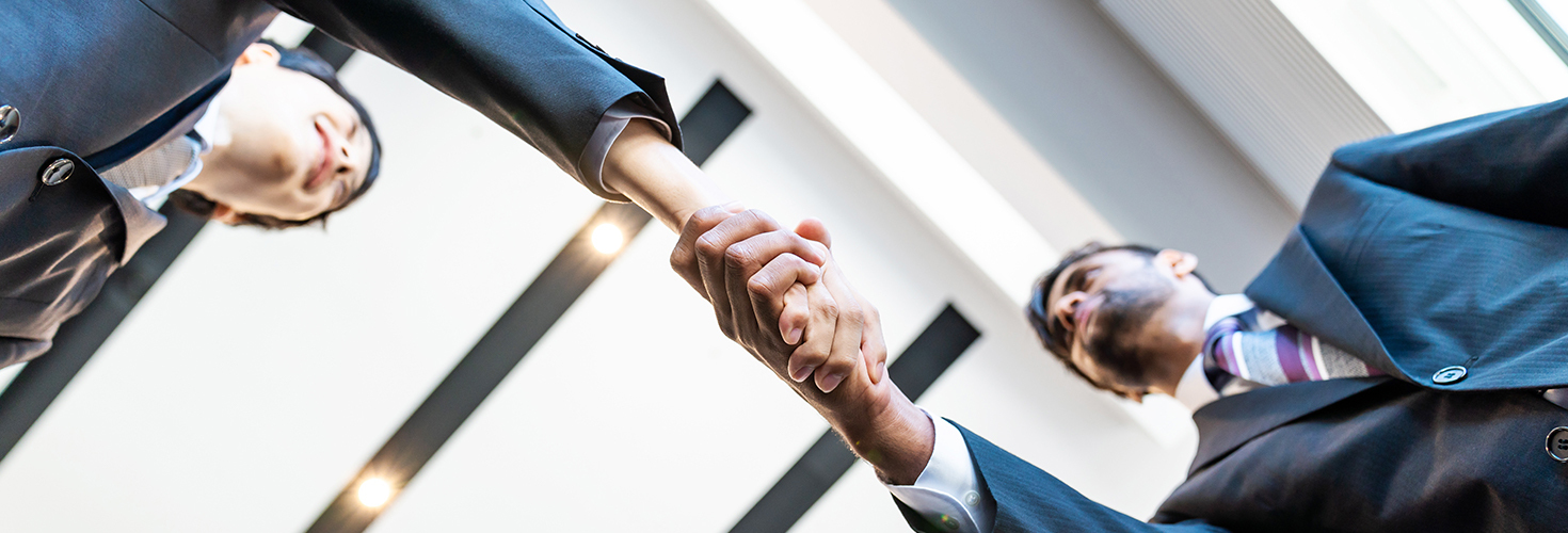 Businessmen shaking hands, photo taken from below