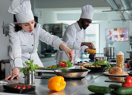 C50 female and male chefs developing dishes in restaurant kitchen