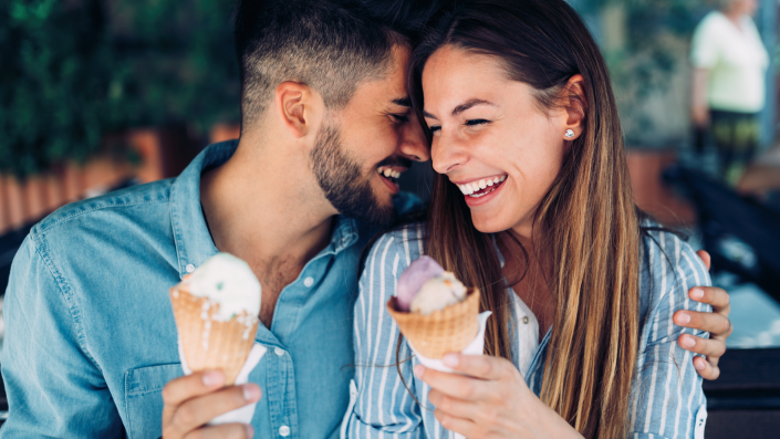 A man and woman share a close laugh while enjoying reduced sugar ice cream cones.