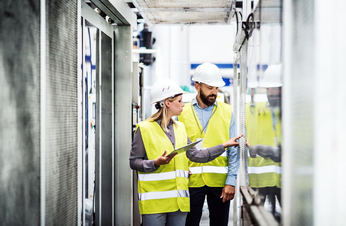 Male and female workers with a tablet at a factory