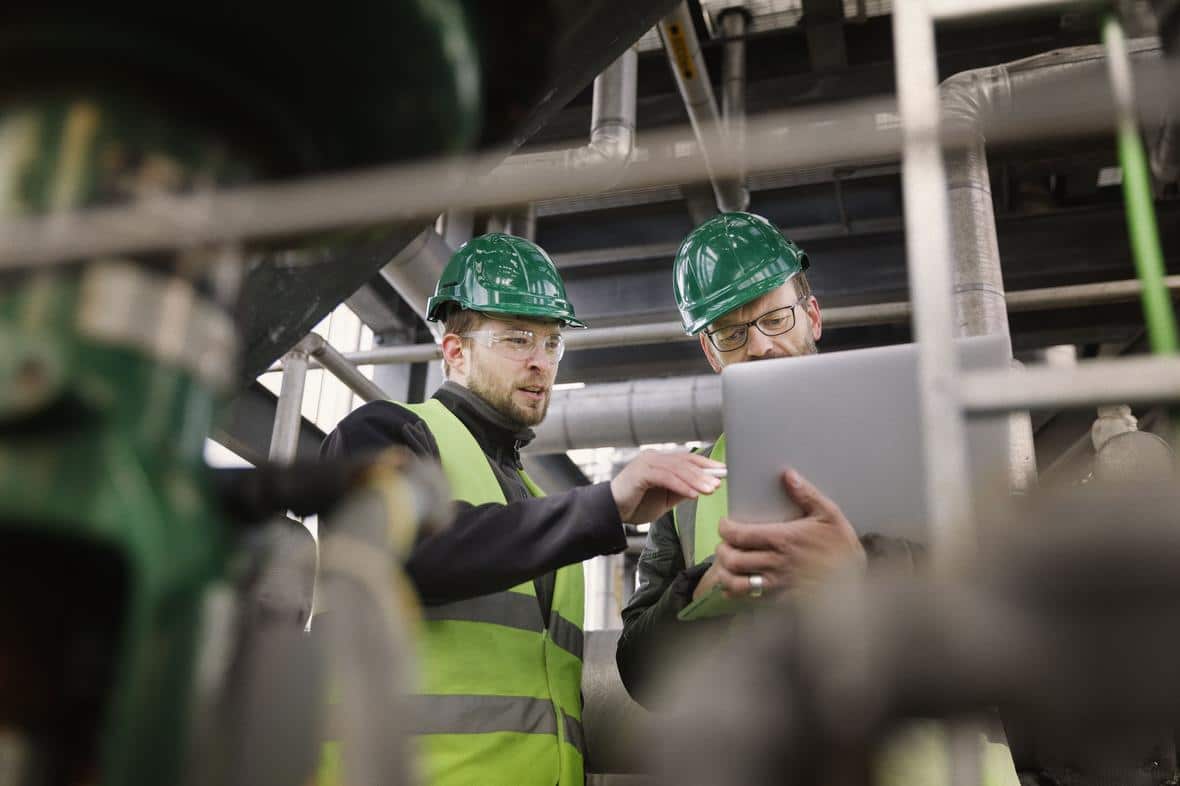 Manual workers discussing while using laptop at factoryGettyImages 490607422 min