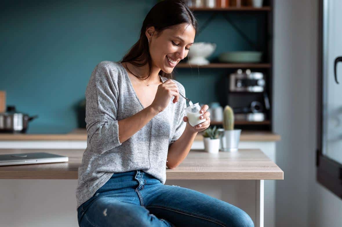 Woman in kitchen enjoying dairy-like yogurt snack