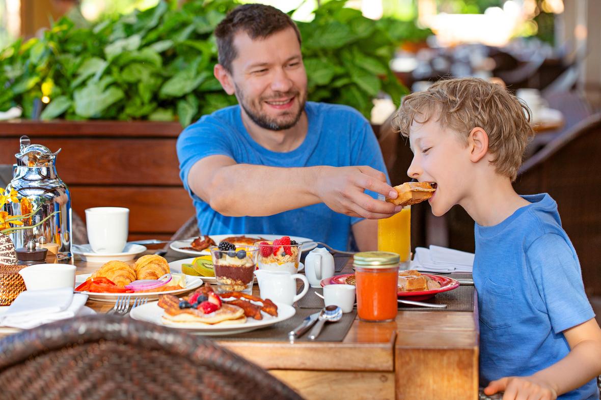 Dad feeding son with a smile 