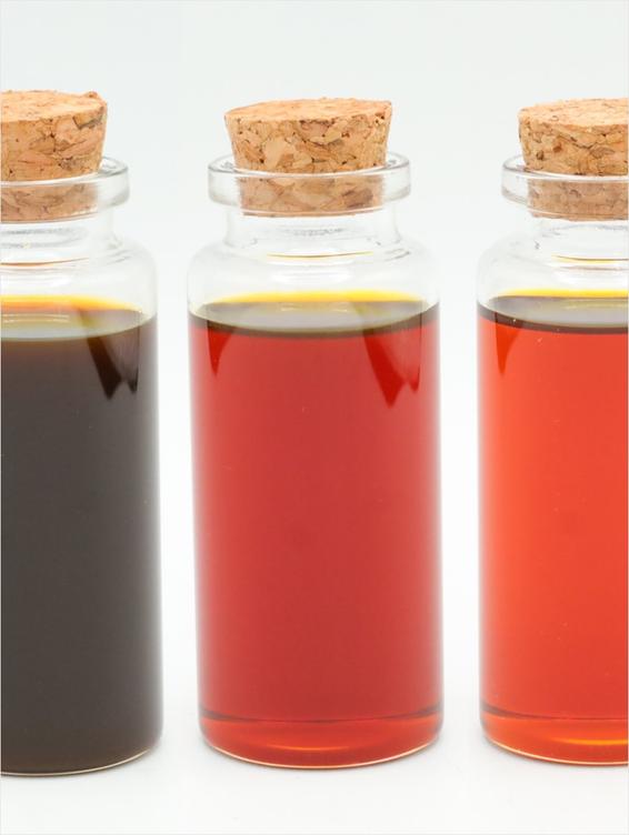 A photo of 3 bottles. The bottles from left to right are different colors. Far left is caramel brown color. Middle bottle is more amber and the last bottle is a lighter amber.