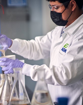 Scientist in a white lab coat performing experiments at ADM